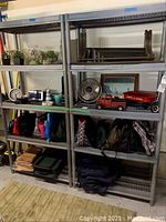 Full view of two of the five gray plastic shelving units installed side-by-side, containing various non-included items like plants, clock, small fan, toy red truck, bags, fabric, and boxes.