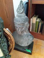 Front three-quarter view of grey terracotta Buddha bust on black rectangular base