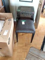 Photo showing the woven seat stool in front of the decorative trunk next to an HP cardboard box.