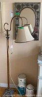 Photo showing the full metal floor lamp with shade and handmade tin mirror in the background, displaying overall appearance and size.