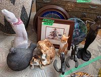 Group of ceramic animal figurines, metal horse silhouettes, decorative plates, and framed signed watercolour on a textured rug