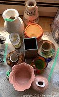 Overview of lot showing various vases, ceramic cups, and pink ruffled bowl