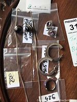 Photo showing two pairs of sterling silver earrings, ring, and chain on table in plastic bags with 925 markings