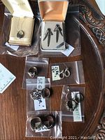 Top view showing entire lot: locket in box, earrings, and eight rings individually bagged with 925 markings visible on some