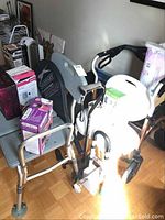 Overview of two grey bath seats, walker frame and boxed items on seats