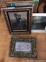 Four framed wall art pieces arranged on the floor showing the black and white print, landscape painting, framed plaque, and another print.