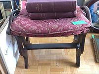 Front view of wooden bench with red floral cushion and two hardcover books on top