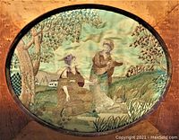 Close-up view of the embroidered and painted silk art depicting two women in a pastoral scene with a baby and tree inside an oval cut wood frame.