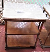 Side view showing one full wood side table with marble top, carved claw feet, and two lower shelves
