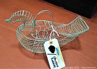 Side view of the vintage chicken-shaped wire basket showing the front side with head and tail, and handle in the middle.
