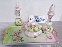 Front view of Nippon dressing table set showing pink and green floral handpainted tray, two perfume bottles with stoppers, and lidded bowl.