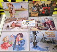 Overview photo showing all six tin metal advertisement signs arranged in two rows on a flat surface