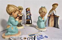 Front view of all five Goebel Hummel figurines arranged in a row showing different poses including praying children and Mary with a halo.