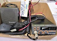 Photo showing the Cobra 19 Ultra Mobile CB radio with microphone and Motorola speaker inside a cardboard box with wires and labels.