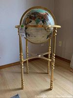 Full view of decorative globe and polished brass tripod stand