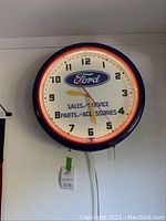 Front view of blue Ford clock with red neon-lit surround and white face showing time and branding.
