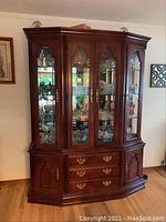 Front view of two-piece breakfront hutch showing mirrored back and glass cabinet above three drawers and side cabinets