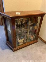 Front view of wooden display case with glass doors showing interior glass shelves and various items inside (not included).