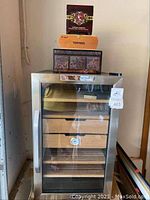 Front view of Whynter humidor with glass door, cedar drawers, and stacked cigar boxes on top