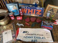 Wide view of collectibles on table showing sign, towel, brass bowl, and various small items