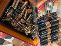 Photo showing multiple batteries in sizes D, C, AA, AAA, and 9V from Duracell and Kirkland brands, both loose and in packaging.