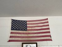 American flag representative of the flag flown at the U.S.S. Arizona Memorial, showing wear and aging with 50 stars and 13 stripes.