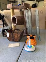 Photo showing cat tree with carpeted tunnels and posts, metal fencing panels, ornate wooden basket with 'pet' label, and orange ball tower toy