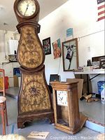 Overall view of grandmother clock and smaller mantel clock and barometer in garage setting