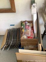 Metal frames or hangers stacked next to a box containing various crafting items including colorful cords and adhesives, possibly related to stained glass crafting.