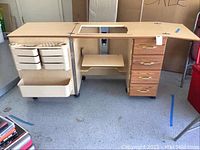 Front angle showing entire wooden cabinet with sewing machine cutout, storage drawers on right, and plastic storage organizers mounted on left side.