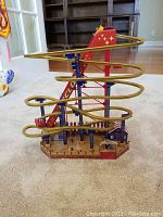Photo of wooden spiral track coaster toy for Christmas with moving cars and decorative Christmas-themed base.