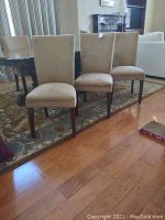 Three chairs side by side front view on area rug beside table