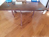 Wooden folding table from a top-side angle showing the entire tabletop and part of the floor.