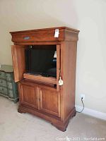 Front view of wooden television cabinet with both upper doors open revealing a television inside. Shows the cabinet's design and wood finish.