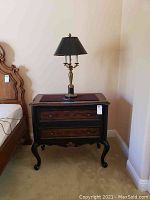 Front view of Hooker Furniture two-drawer nightstand with decorative lamp on top, showing ornate details and leg style.