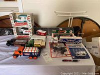 Wide view of assorted die-cast metal bank trucks and collectible toy trucks on table, some boxed and some loose.