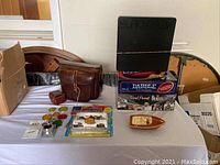 Overview photo showing the grouping of the toy tanks, wooden boat, board games, camera case, and filters arranged on table.