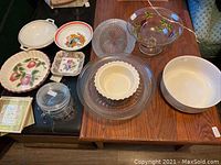 Full view of all items on wooden table including bowls, dishes, trivets, and glassware