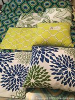 Photo showing three square pillows with zippers and three additional matching pillow covers featuring floral and geometric patterns in blue, green, and yellow colors.