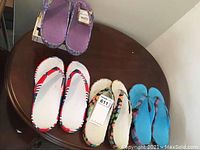 Overview photo showing all four pairs of Dawgs flip flops on a round wooden table.
