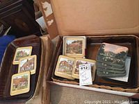 Photo of both Pyrex casseroles in their wicker holders within original boxes, alongside two sets of cork-backed scenic coasters.