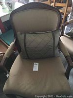 Front view of striped armchair with green pillow placed on seat, showing wooden frame and upholstery.