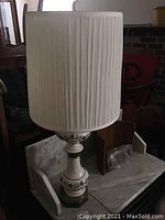 Side view of ceramic table lamp showing pleated white fabric shade and ceramic base with green ivy design
