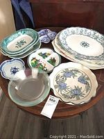 Overview of all dishes arranged on a table showing various transferware platters, clear glass bowls, blue bowls, and divided dish.