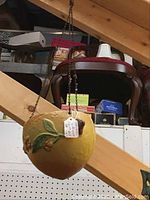Full view of yellow Roseville Buttercup hanging planter suspended from ceiling with metal chain. It shows rounded form with floral details on surface.