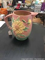 Full side view of the pink Roseville Peony pitcher showing the floral design and handle.
