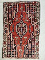 Full view of the hand knotted wool Persian rug showing geometric design in red, black, and white with floral border details.