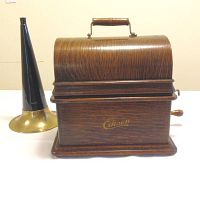 Front view of closed wooden phonograph with horn beside it