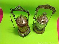 Two jars side by side showing clear and red glass liners in silver plated frames on green background