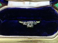 Engagement ring centered in open velvet box showing three-stone diamond setting